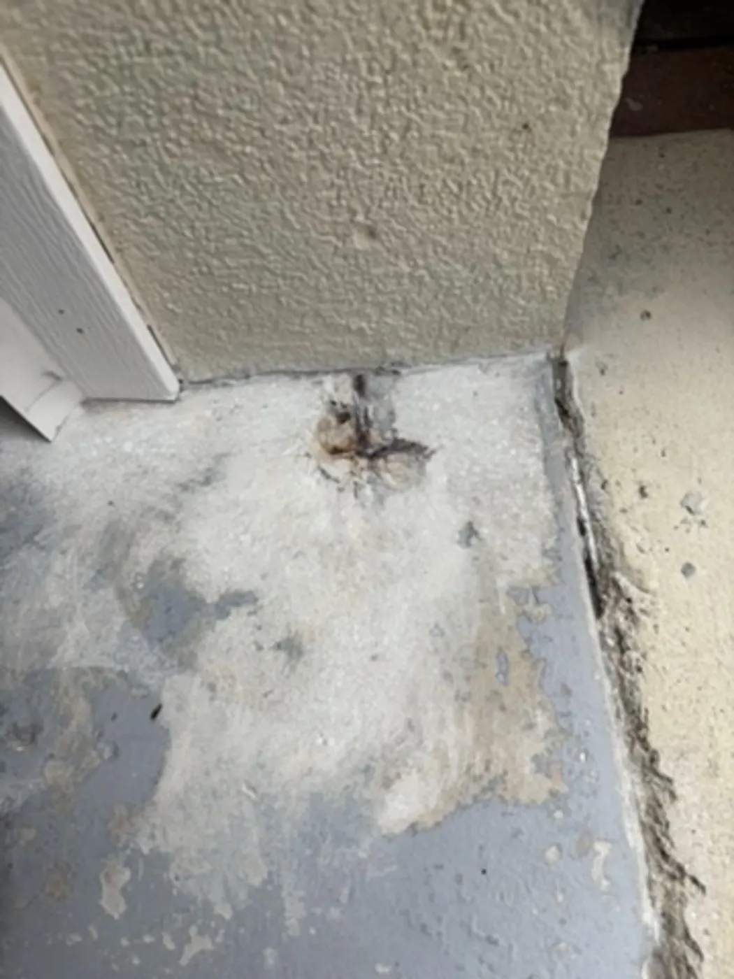 Damaged garage floor corner patched before epoxy coating
